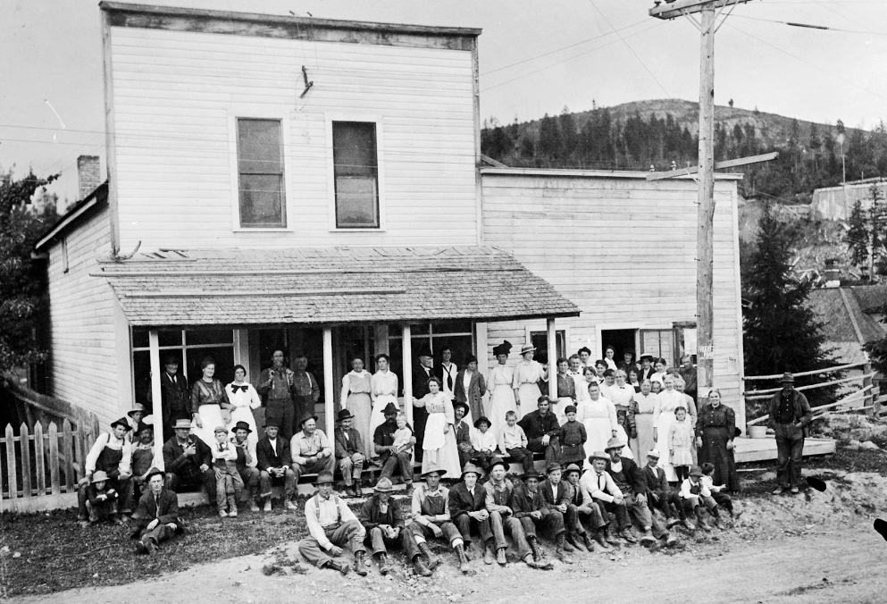 Group gathered for "Good Roads Day" celebration at building on the east side of Bridge Street. Good Roads Day was a community event for improving Electric Avenue--stump removal, etc. The writing on the back of this photo reads, "A.M. Hart", who was Addie Hart and was Jay Whitney's great-grandmother. Circa 1910.  Credit - Whitney Family Collection